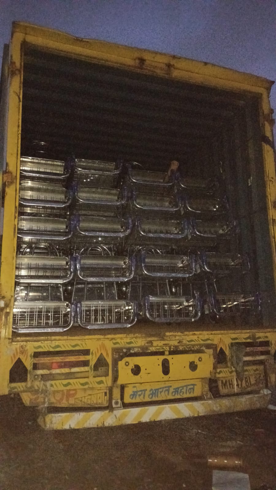 Container truck fully loaded with stainless steel airport trolleys at night