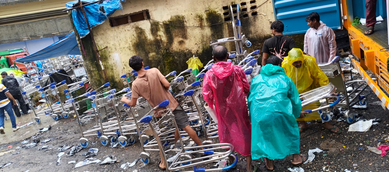 Ground crew moving airport luggage trolleys outside manufacturing facility Mumbai